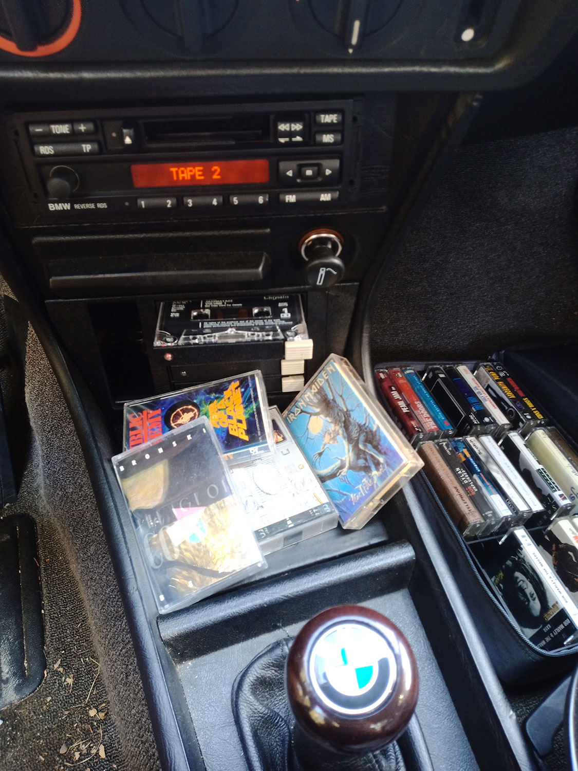 Close-up of the period BMW cassette deck and tapes inside the E21 — product photography detail
