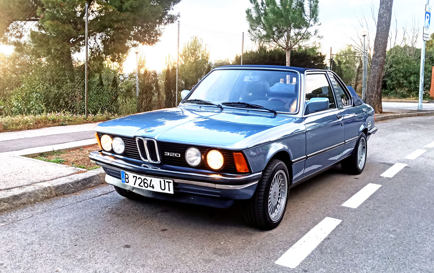 1981 BMW E21 Baur convertible in Stratosblau Metallic, photographed front three-quarter at golden hour on an open road