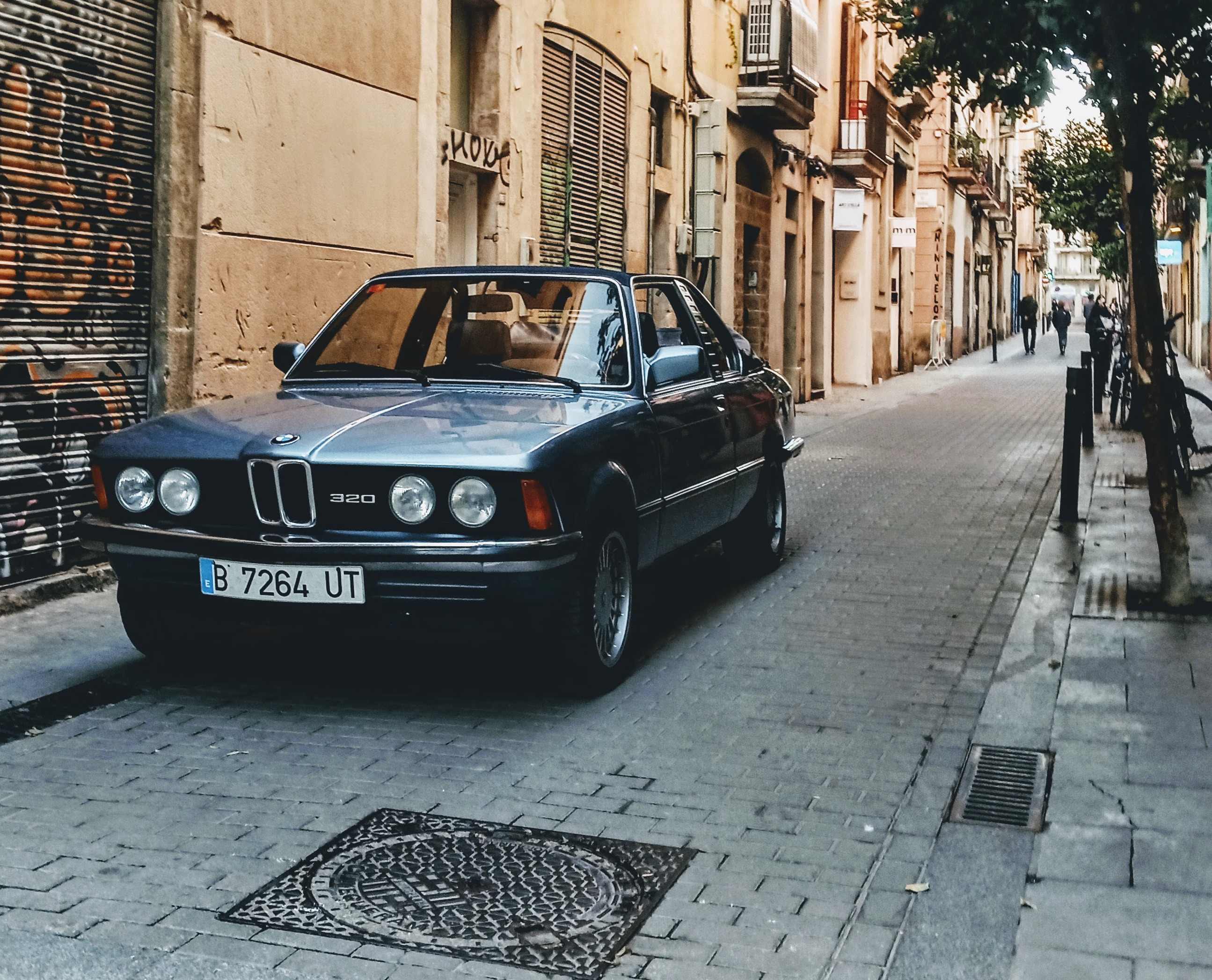 Front three-quarter of the BMW E21 on a Barcelona Gothic-quarter street