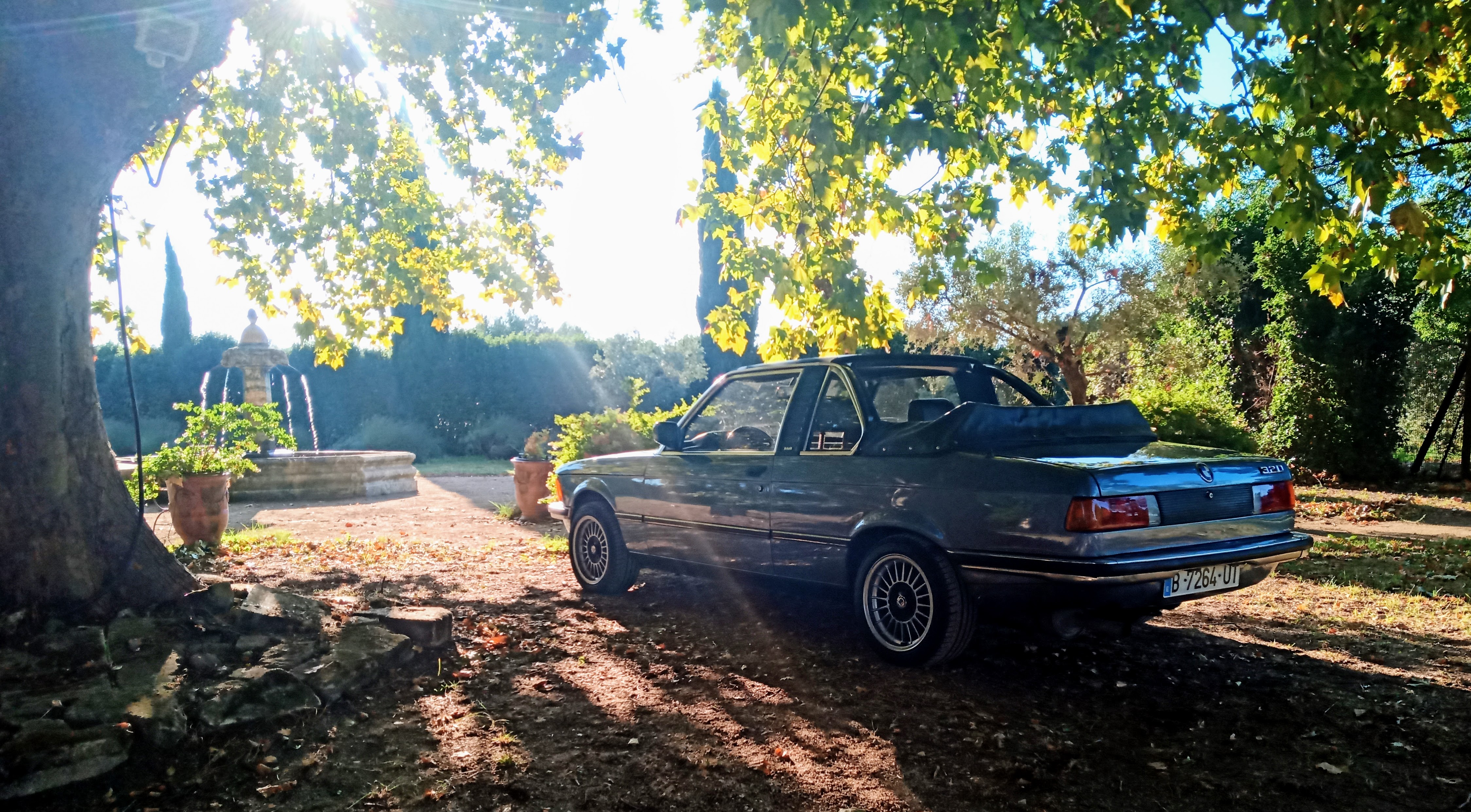 BMW E21 with its Baur roof open in a sunlit garden — wedding and portrait context
