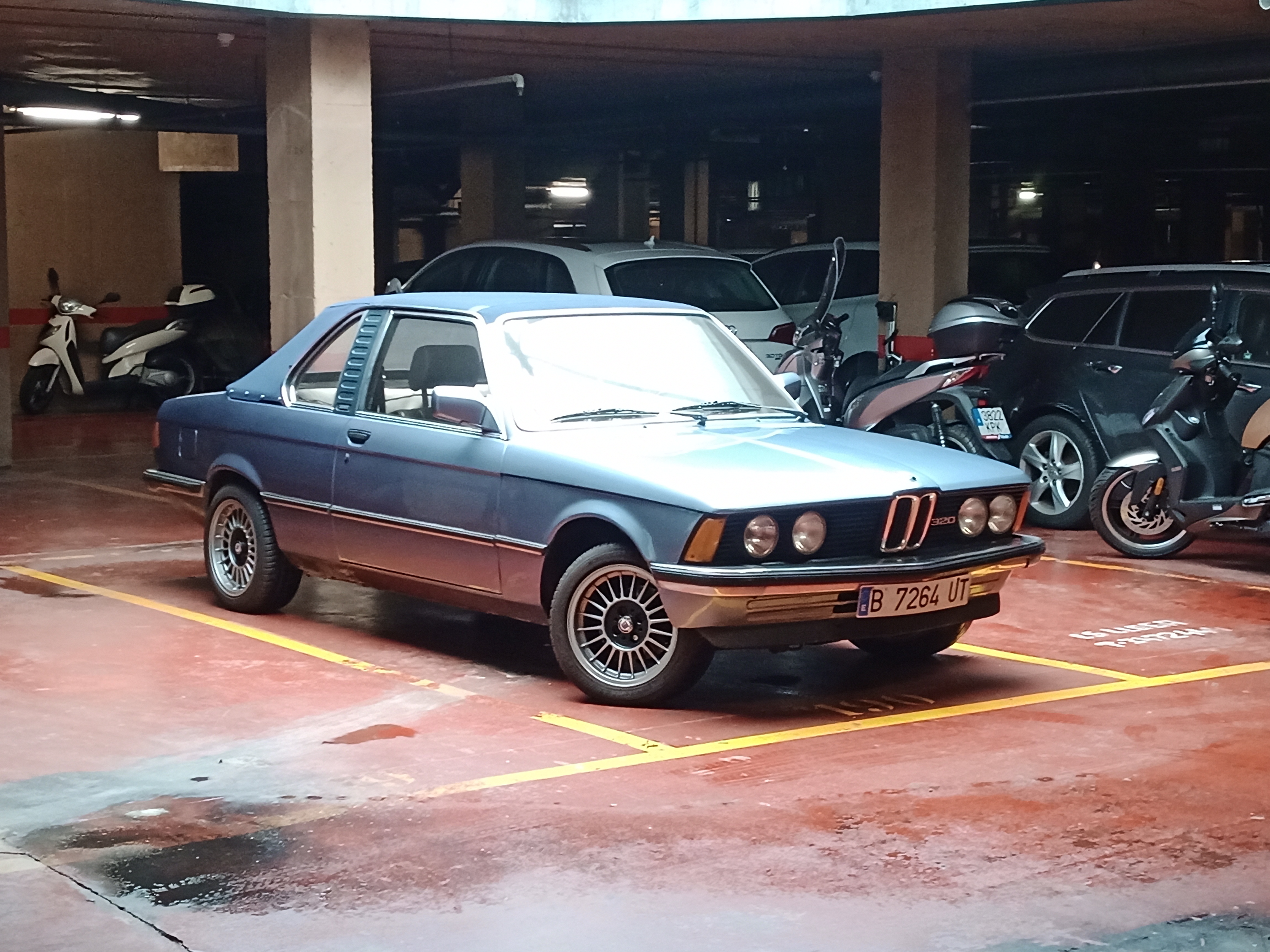 Side-profile view of the BMW E21 in a parking garage
